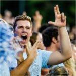 GVSU student shows the Anchor Up hand sign during a football game.